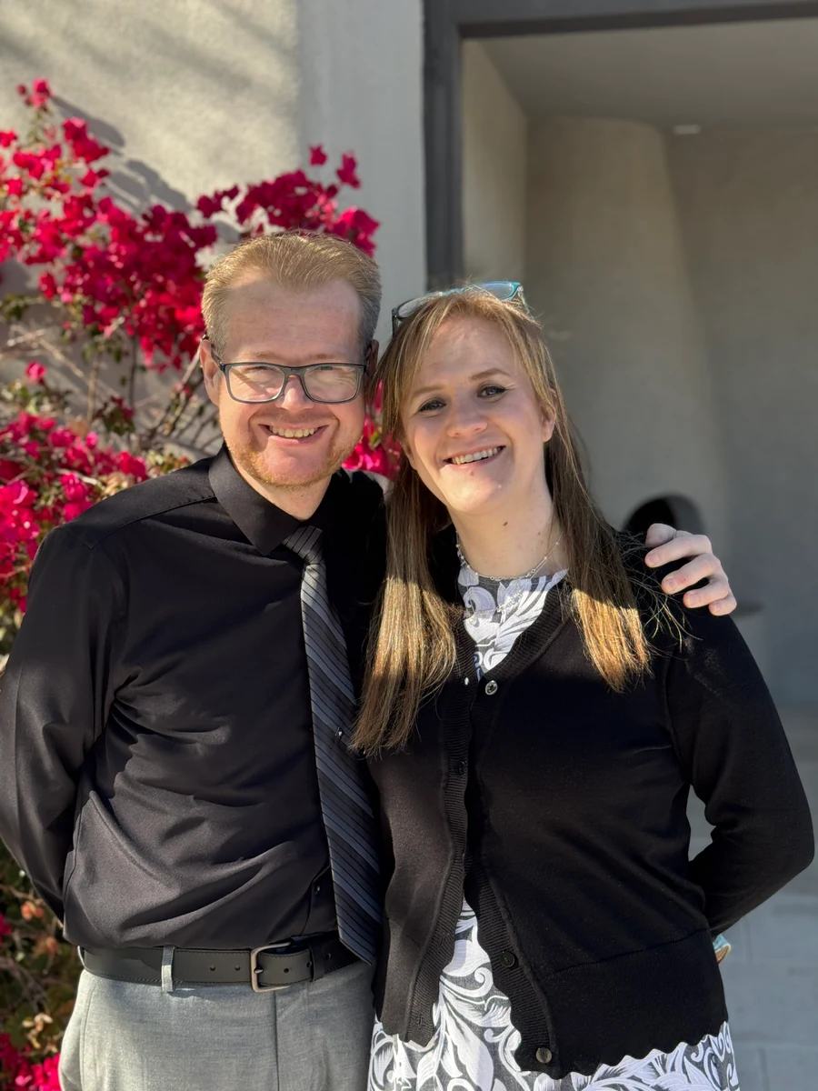 David and Sandra smiling together beside pink flowers